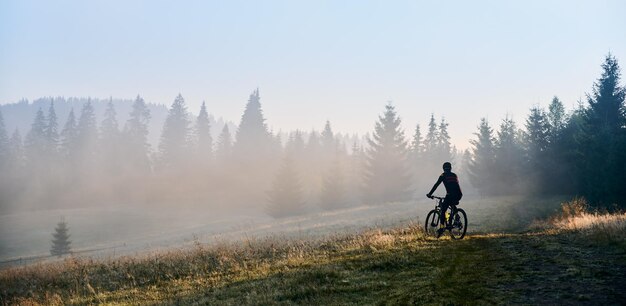 Młody mężczyzna jedzie na rowerze w górach wczesnym rankiem