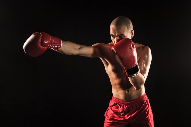 Młody mężczyzna kickboxingu sportowca na czarnym tle