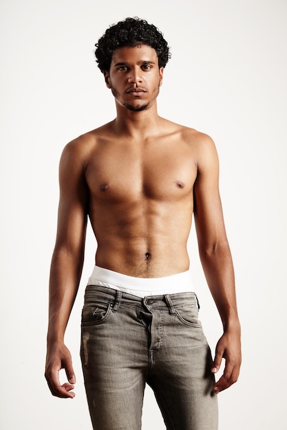Młody mężczyzna nosi dżinsy, pokazując mniej koszulki z idealnym ciałem