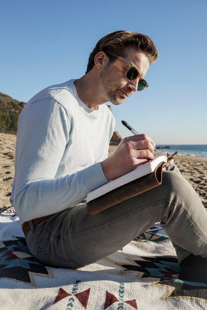 Młody mężczyzna pisze w swoim agendzie na plaży
