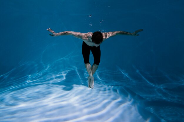 Młody mężczyzna pozuje zanurzony pod wodą