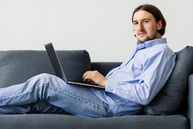 Młody mężczyzna pracujący na laptopie na kanapie