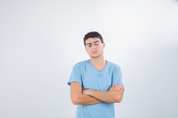 Młody mężczyzna stojący ze skrzyżowanymi rękami w t-shirt i patrząc rozczarowany, widok z przodu.