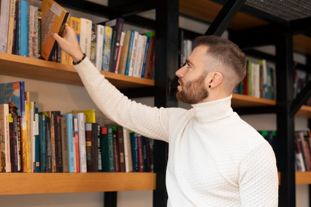 Młody mężczyzna szuka książek w bibliotece do nauki