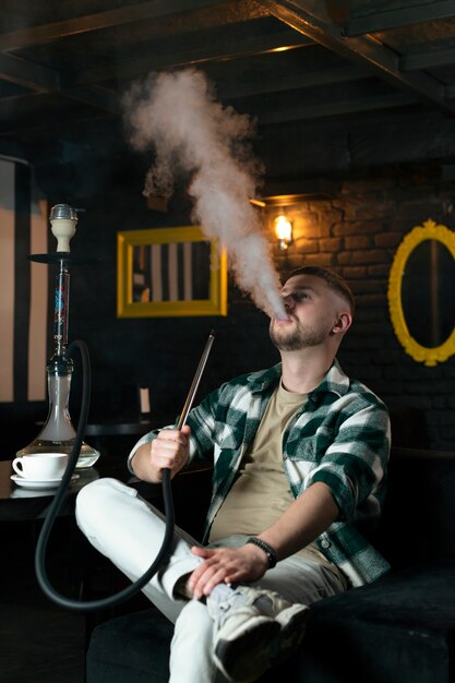 Młody mężczyzna vaping z fajki wodnej w barze