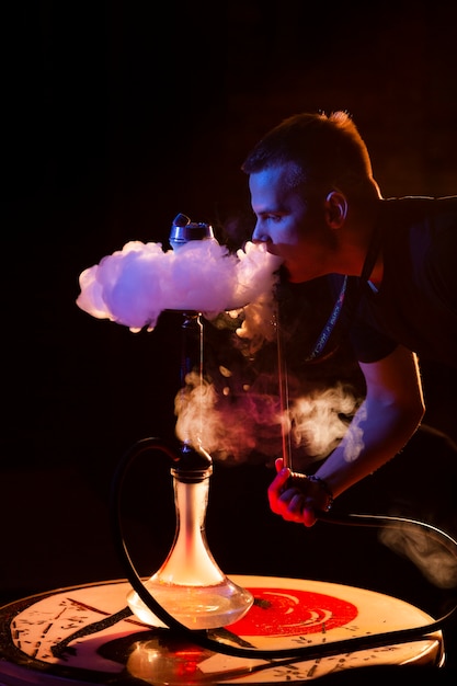 Młody mężczyzna vaping z fajki wodnej w barze