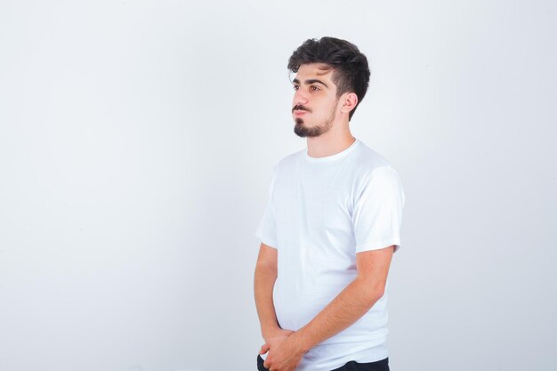 Młody mężczyzna w białej koszulce odwracający wzrok i zamyślony