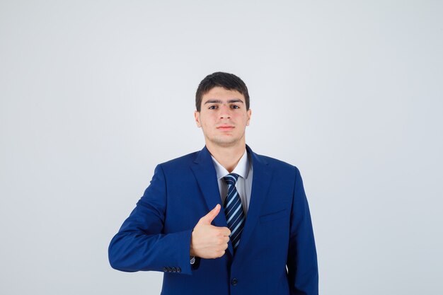 Młody mężczyzna w formalnym niebieskim garniturze pokazując kciuk do góry