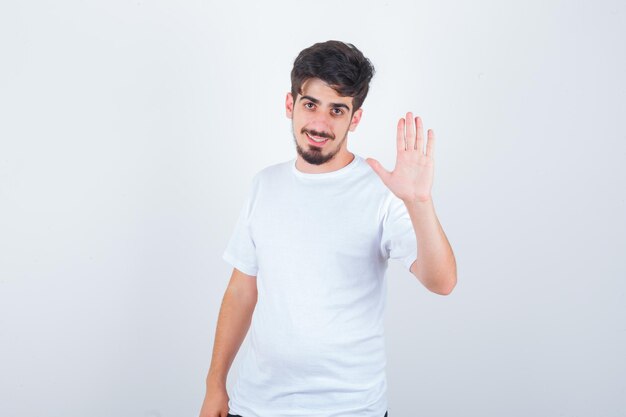 Młody mężczyzna w koszulce pokazujący dłoń i wyglądający uroczo