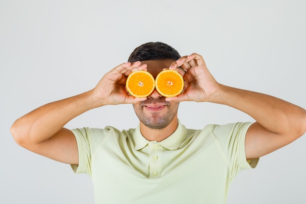Bezpłatne zdjęcie młody mężczyzna w koszulce, trzymając pomarańczowe plasterki na oczach