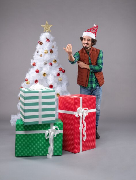 młody mężczyzna wokół świątecznych prezentów na szaro