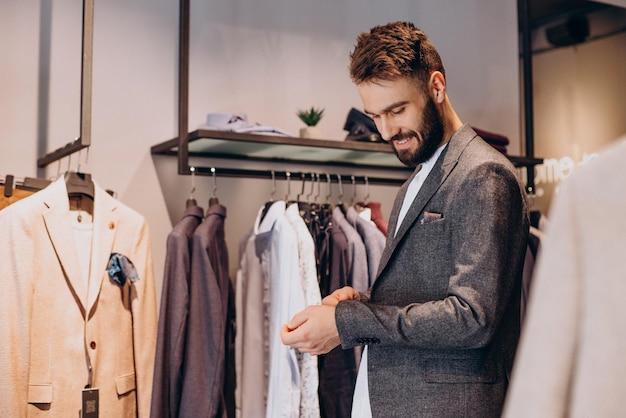 Bezpłatne zdjęcie młody mężczyzna wybierający ubrania w sklepie z odzieżą męską