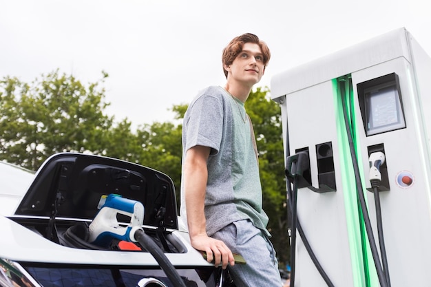 Bezpłatne zdjęcie młody mężczyzna z elektrycznym samochodem na stacji ładującej w kiszyniowie w mołdawii