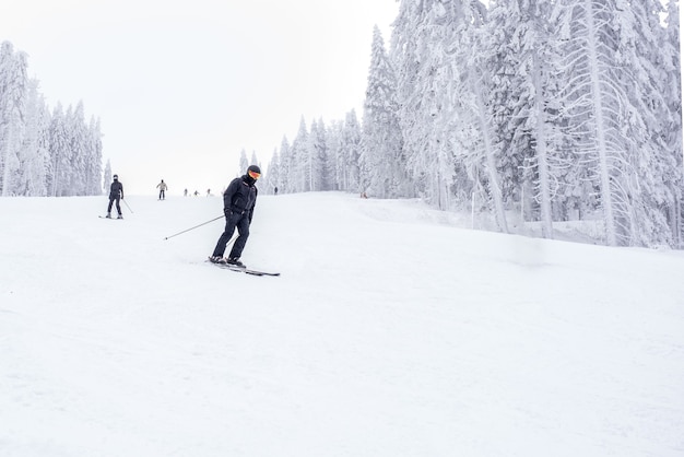 Młody narciarz w ruchu w górskim ośrodku narciarskim z pięknym zimowym krajobrazem w tle