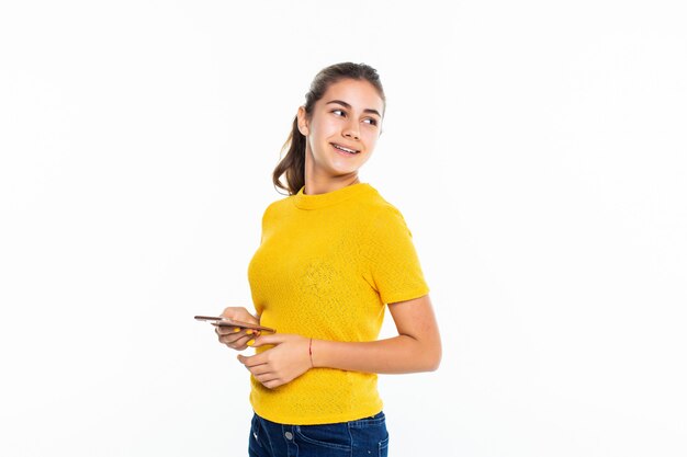 Młody nastoletni dziewczyny use telefon komórkowy odizolowywający na biel ścianie