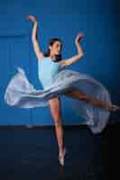 Bezpłatne zdjęcie młody nowożytny baletniczy tancerz pozuje na błękicie
