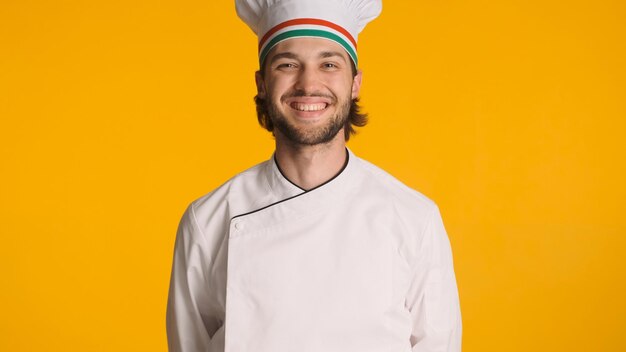 Młody, odnoszący sukcesy szef kuchni ubrany w mundur, uśmiechający się do kamery na kolorowym tle Atrakcyjny mężczyzna gotowy do gotowania pysznego jedzenia Pozytywna ekspresja