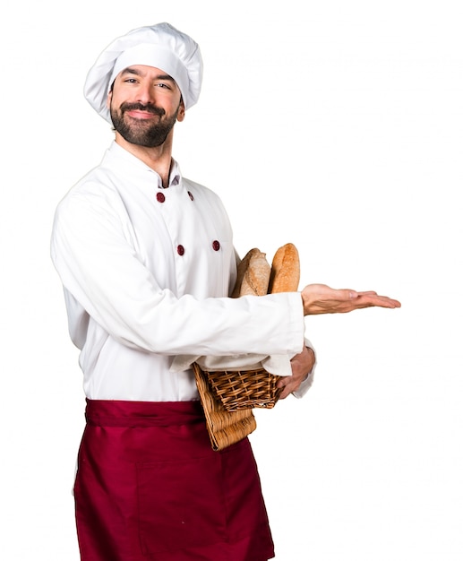 Młody piekarz trzyma chleb i prezentuje coś