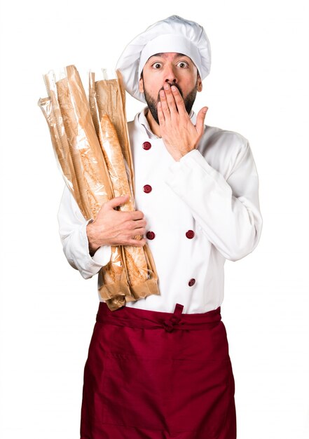 Młody piekarz trzyma chleb i zaskoczony gest