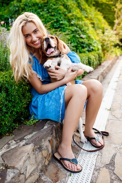 Bezpłatne zdjęcie młody piękny blondynki dziewczyny odprowadzenie, bawić się z beagle psem w parku.