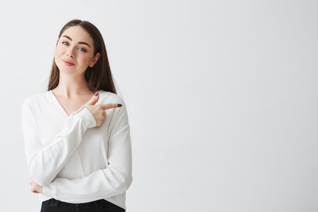 Młody piękny brunetka bizneswoman uśmiecha się wskazujący palec w stronie.