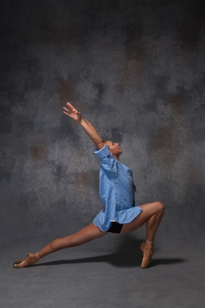 młody piękny nowoczesny styl tancerz w niebieskiej koszuli pozowanie na szarym tle