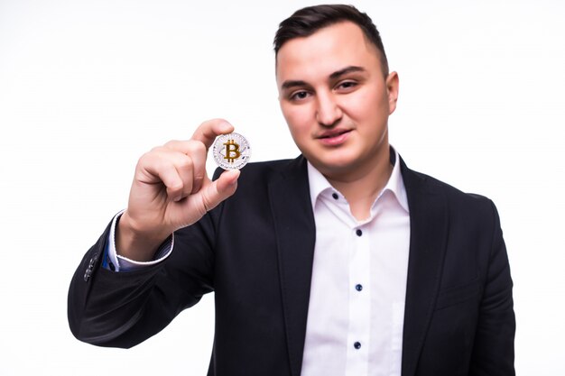 Młody podekscytowany mężczyzna na białym tle trzyma w rękach monetę bitcoin