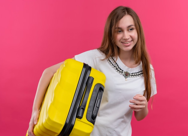 Młody podróżnik dziewczyna trzyma walizkę na na białym tle różowej ścianie