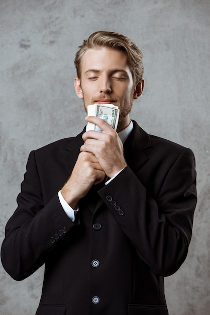 Bezpłatne zdjęcie młody pomyślny biznesmen w kostiumu mienia pieniądze
