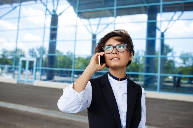 Młody pomyślny bizneswoman mówi na telefonie, stojący blisko centrum biznesu.