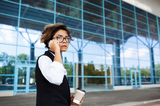 Młody pomyślny bizneswoman mówi na telefonie, stojący blisko centrum biznesu.