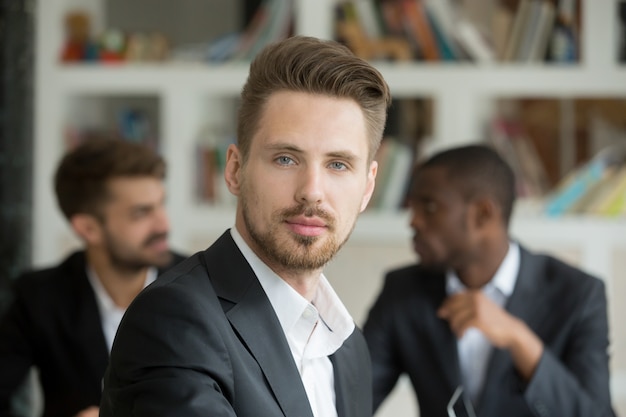 Młody poważny biznesmen patrzeje kamerę na spotkaniu, headshot portret