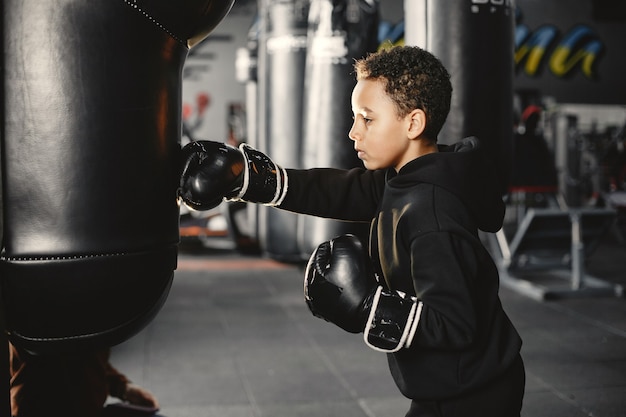 Młody pracowity bokser uczy się boksować. Dziecko w centrum sportowym. Dziecko podejmuje nowe hobby