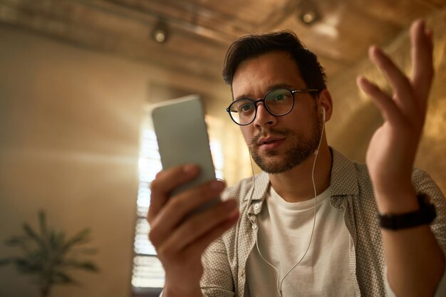 Młody przedsiębiorca niepewny smsa, który otrzymał na smartfonie w biurze