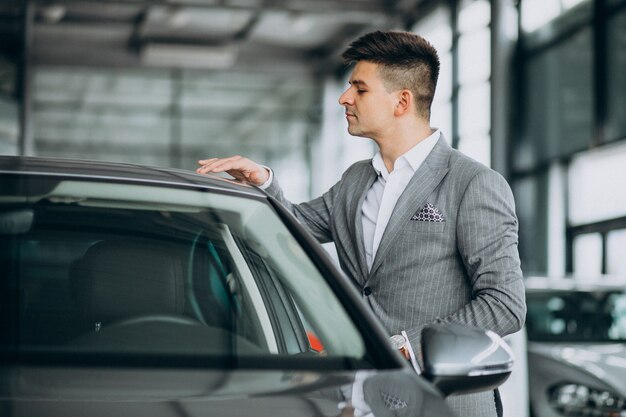 Młody przystojny biznesowy mężczyzna wybiera samochód w samochodowej sala wystawowej