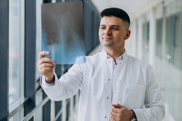 Młody przystojny chirurg patrzeje promieniowanie rentgenowskie
