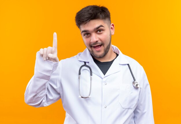 Młody przystojny lekarz ubrany w białą suknię medyczną białe rękawiczki medyczne i stetoskop