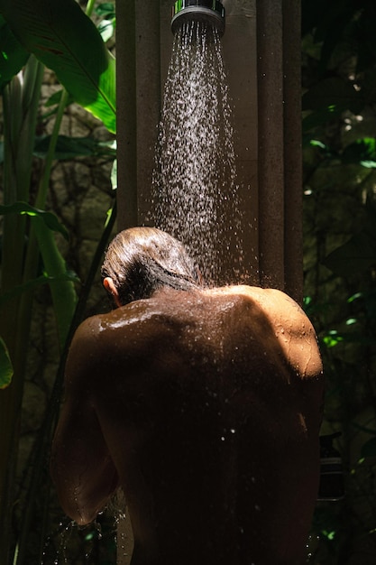 Młody przystojny mężczyzna myje się pod prysznicem, atletyczna budowa ciała, tatuaże.