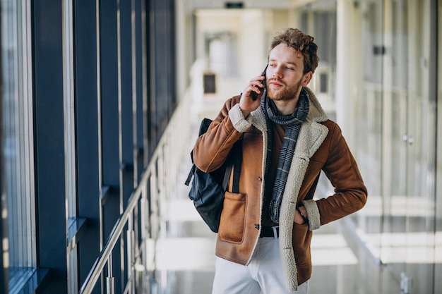 Młody przystojny mężczyzna na lotnisku rozmawia przez telefon