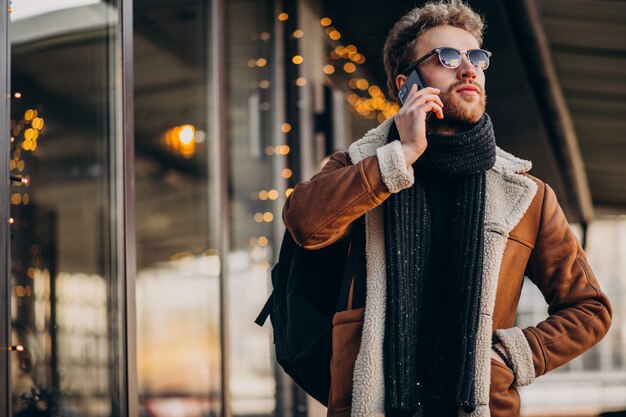 Młody przystojny mężczyzna opowiada na telefonie lotniskiem