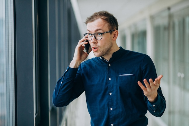 Młody przystojny mężczyzna rozmawia przez telefon w biurze