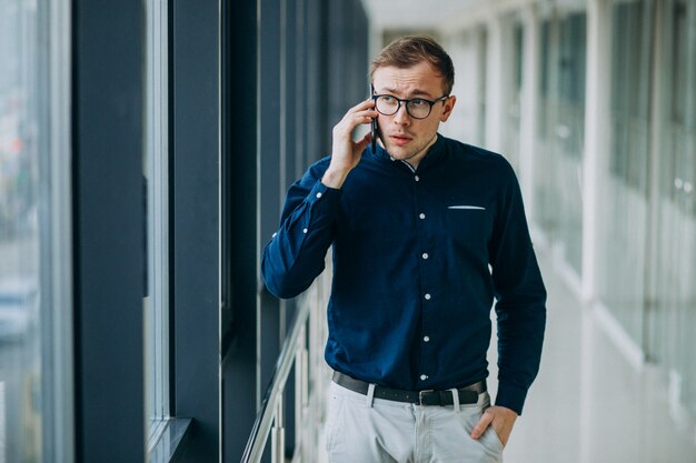 Młody przystojny mężczyzna rozmawia przez telefon w biurze