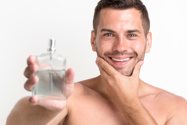 Młody przystojny mężczyzna uśmiechający się Wyświetlono balsam po goleniu sprayem