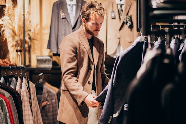 Młody przystojny mężczyzna wybierać odziewa przy sklepem