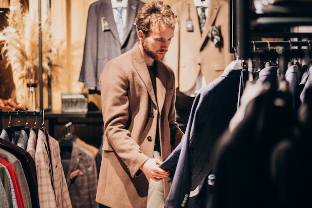 Młody przystojny mężczyzna wybierać odziewa przy sklepem