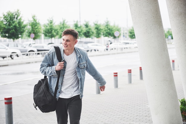Bezpłatne zdjęcie młody przystojny mężczyzna z torbą na ramieniu w pośpiechu na lotnisko.