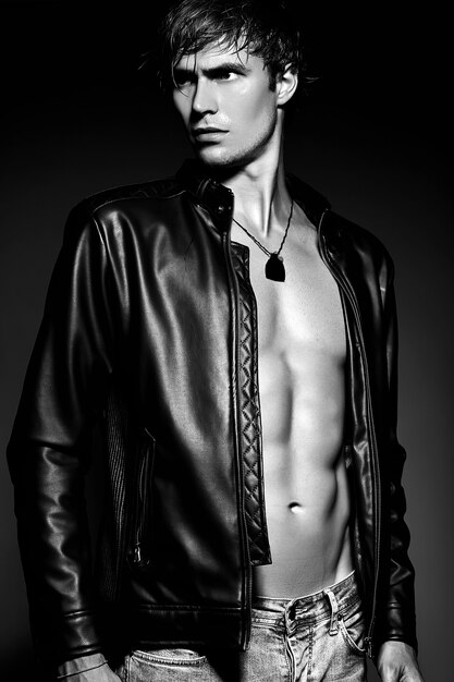 Młody przystojny umięśniony sprawny mężczyzna model mężczyzna pozowanie Studio pokazując swoje mięśnie brzucha w skórzanej kurtce