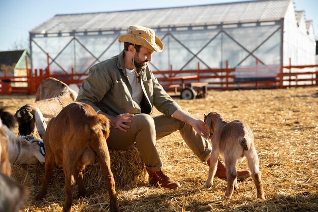 Młody rolnik spędzający czas ze swoimi kozami na farmie
