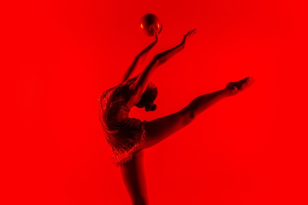 Młody sportowiec gimnastyka na białym tle na ścianie czerwony studio