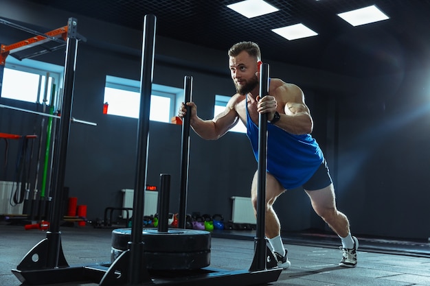 Młody sportowiec mięśni, trening w siłowni, ćwiczenia siłowe, ćwiczenia